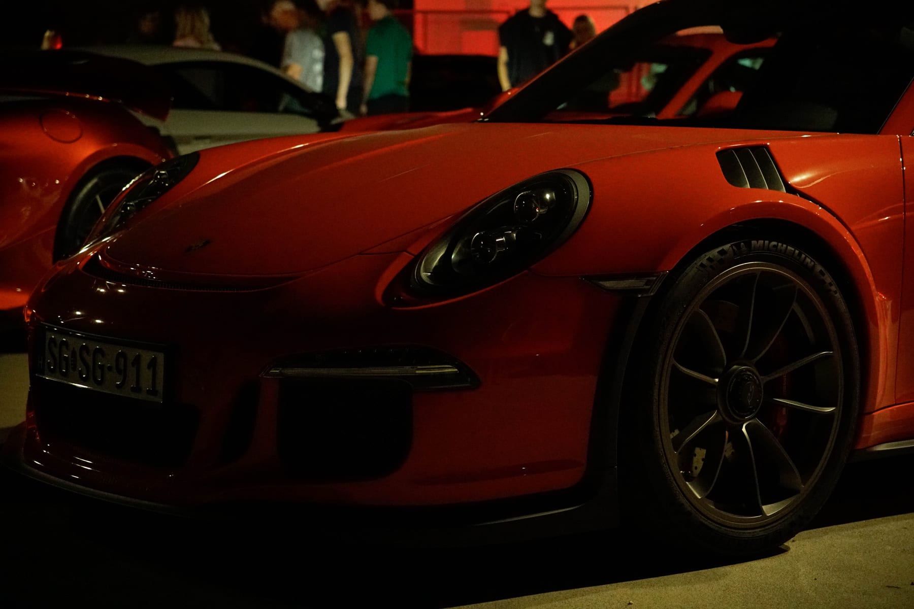 Red Porsche 911 GT3 RS under red light at a car meet